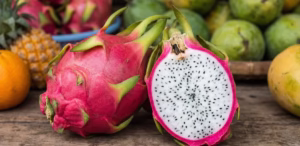Fresh white-flesh dragon fruit from Vietnam with sliced pieces displayed among tropical fruits
